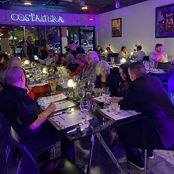 Diners seated at tables under purple lighting in Costanera Peruvian Cuisine restaurant.