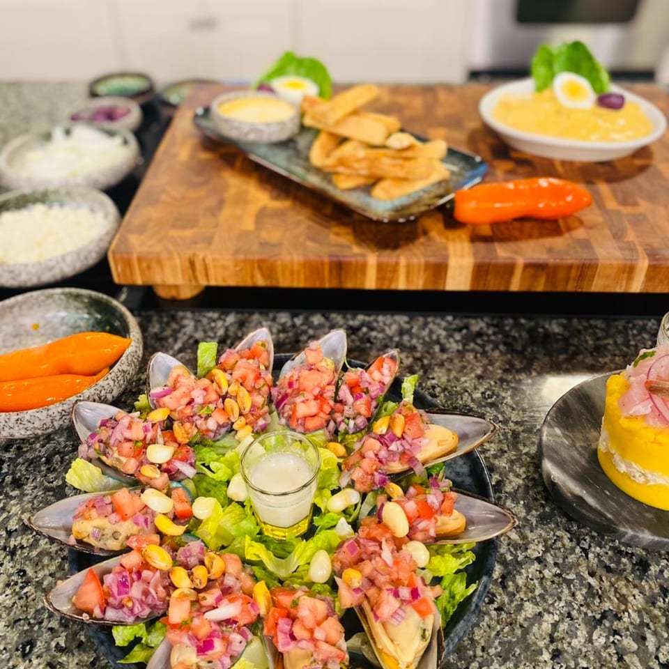 Peruvian mussels a la chalaca, causa rellena, and fried yucca with dipping sauce on a granite counter.