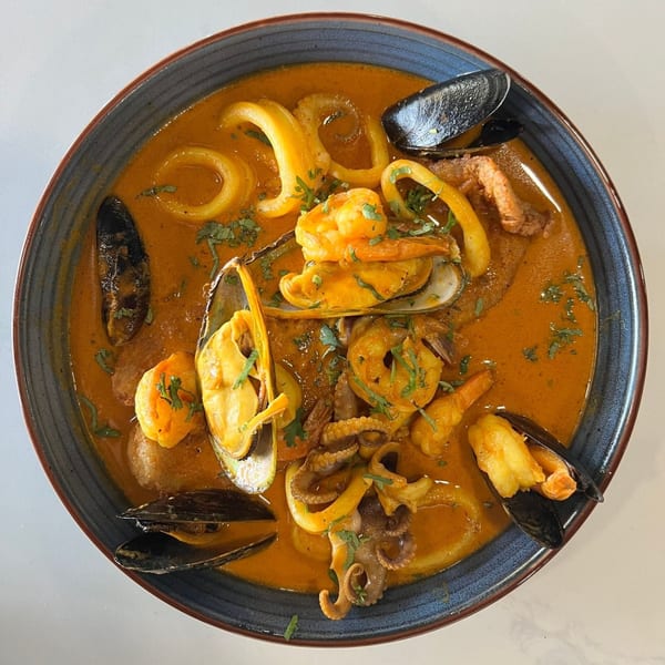 Peruvian seafood soup with shrimp, mussels, squid, and octopus in a rich orange broth.