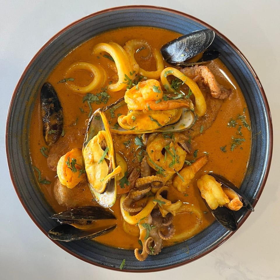 Peruvian seafood soup with shrimp, mussels, squid, and octopus in a rich orange broth.