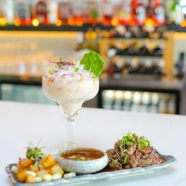 Peruvian ceviche in a glass, with a side of lomo saltado and a dipping sauce.