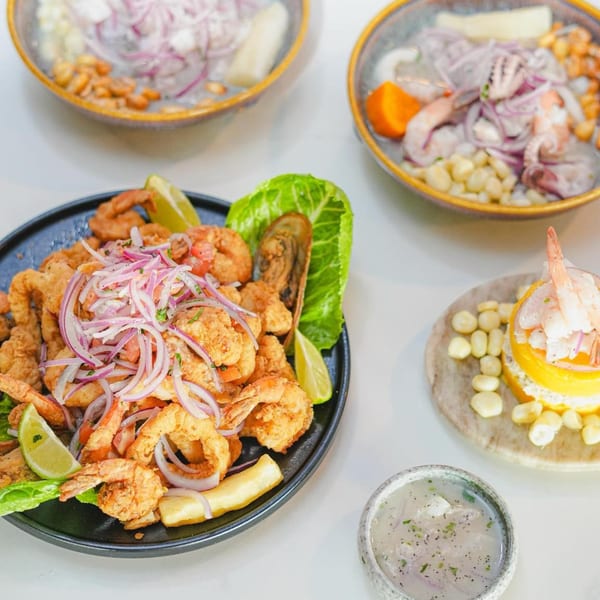 A vibrant spread of Peruvian seafood dishes, including fried shrimp, ceviche, and causa.