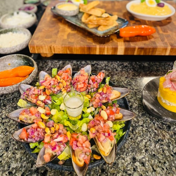 Peruvian mussels topped with diced tomatoes, red onions, and corn, served on lettuce with a sauce.
